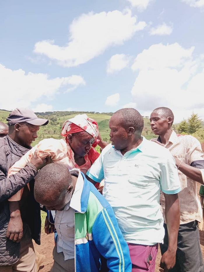 Photo shows a man with a severe head wound wrapped in a white cloth, being carried under the arms by four other men. The injured man in Kibet Emanuel, a Mosopisyek man shot by UWA rangers in 2025.