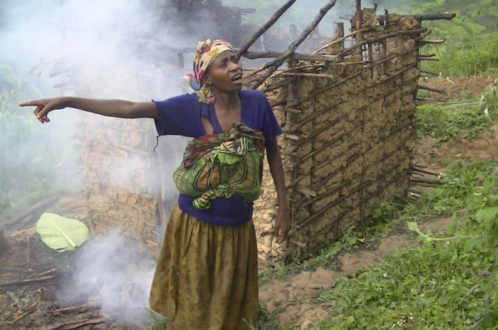 Batwa woman in front of her burning home in Rubuguri, Uganda