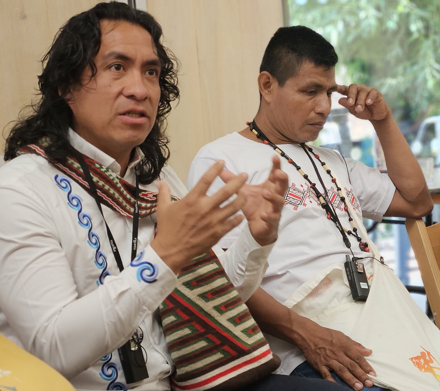 Two men sat down, one is talking and waving his hands. 