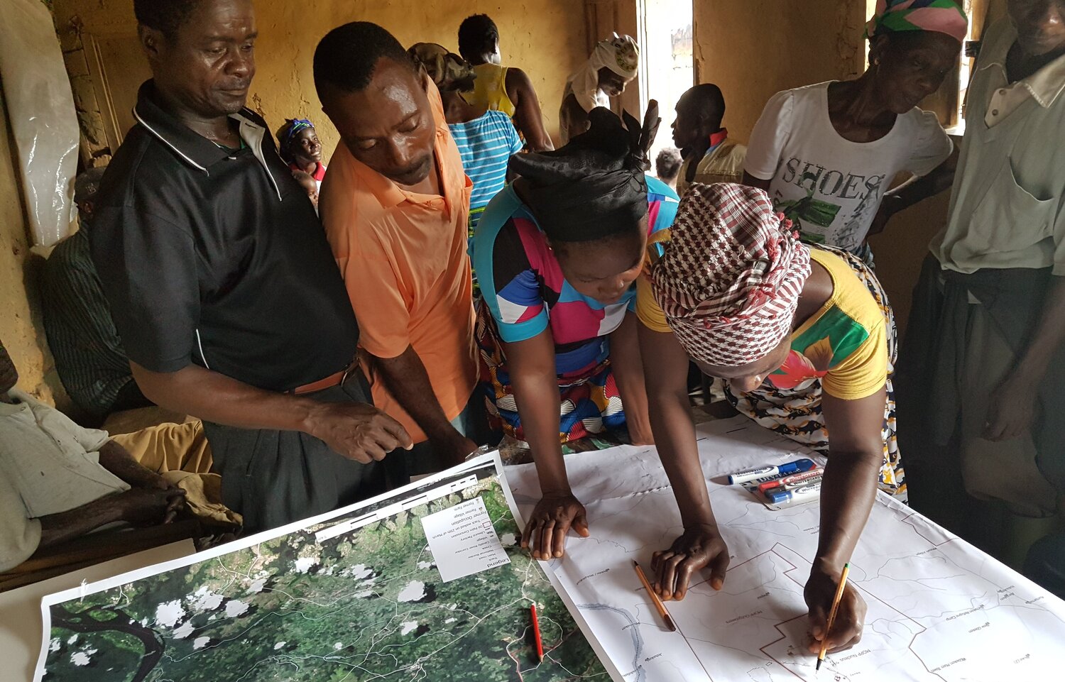 A group of people in a room over a map. 