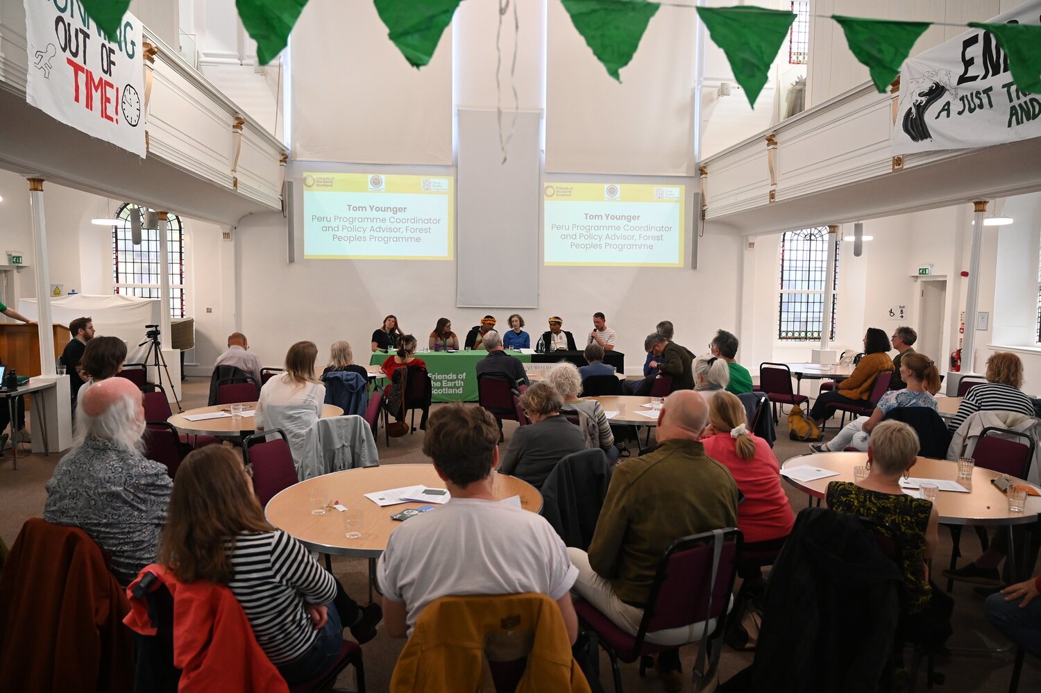 A room full of people with five panellists sat at the front