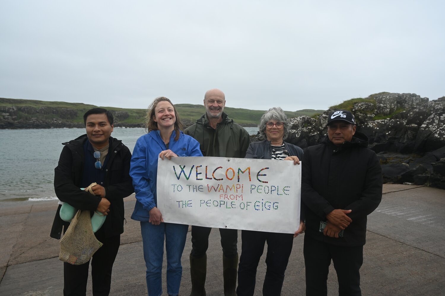 5 people holding a sign that says 'Welcome to the Wampi people from the people of Eigg"