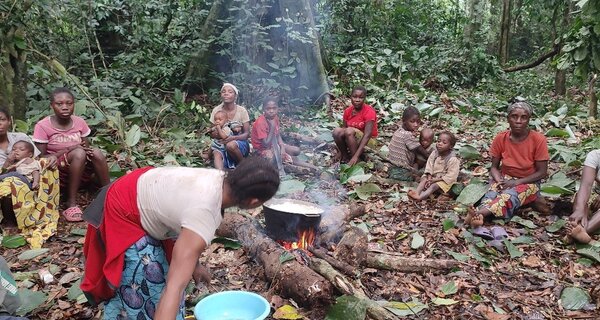 a group of people around a campfire eating and resting