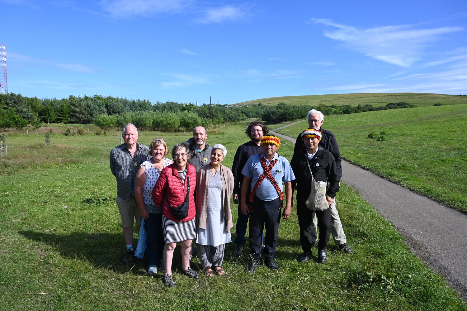 A group of people stood posing for a picture outside surrounded by grass