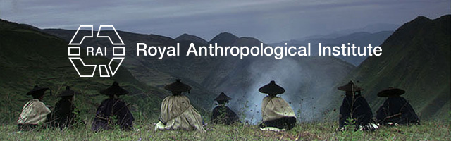 Horizontal image depicting the backs of eight people sitting on a hillside. The people are Wampis. Over the top of the image is some text which says 'Royal Anthropological Institute'